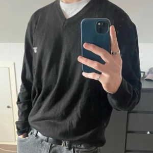 Svart v-ringad tröja från Gant - Svart v-ringad tröja från Gant med diskret logga på bröstet. Tröjan har lång ärm och är tillverkad i mjukt material som passar perfekt till jeans eller chinos. Enkel och stilren design som funkar till många olika looks. Storleken är XXL men är betydligt mindre:)