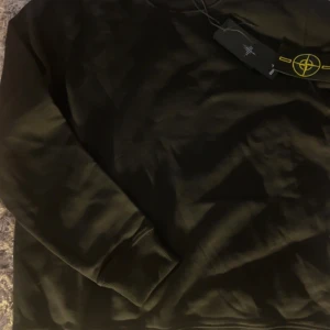 Svart sweatshirt från Stone Island M - Svart långärmad sweatshirt från Stone Island i bomull. Klassisk passform med ribbade muddar och ikonisk logotyp-patch på ärmen. Perfekt för dig som gillar streetwear och vill ha en clean look med snygga detaljer.