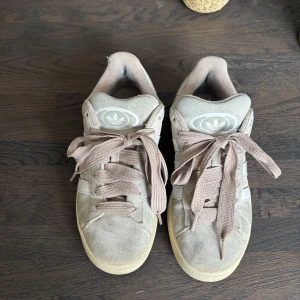 Beige Adidas Campus sneakers - Snygga Adidas Campus sneakers i beige  med klassiska vita ränder och breda rosa/beiga skosnören.  Liten skrevs på sulan (finns bild) annars är de bra skick! För fler bilder skriv❤️st är 38 2/3 men passar mig perfekt som är en ren 38