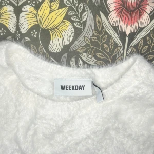 Vit fluffig väst från Weekday - Supermjuk och fluffig vit väst från Weekday med rund halsringning. Västen har en enkel och stilren design utan knappar eller dragkedja, perfekt att slänga över en t-shirt eller skjorta för en trendig look.