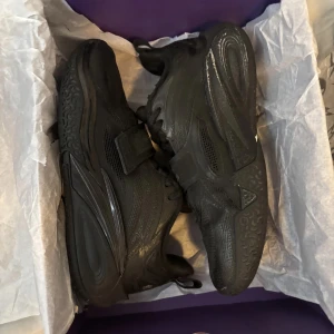 KAI ANTA 1 - Svarta basketskor från ANTA Snygga detaljer och kardborreband över snörningen ger extra stabilitet. Perfekta för dig som vill sticka ut på basketplanen.