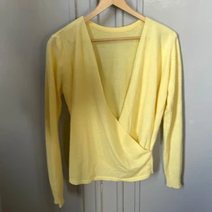 Gul omlottopp med lång ärm från ASOS - SnyggGul omlottopp med lång ärm från ASOS ljusgul omlottopp från ASOS med lång ärm och djup v-ringning. Tunn och mjuk i 100% akryl, perfekt för vår och sommar. Enkel att styla till jeans eller kjol för en fräsch look.