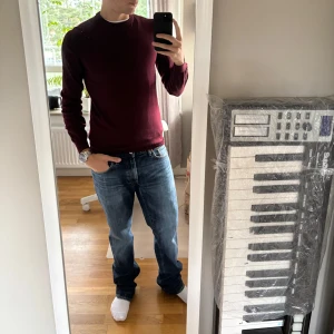 Vinröd stickad tröja med rund hals - Snygg vinröd stickad tröja med rund hals och långa ärmar. Perfekt för dig som gillar stilrena och enkla plagg. Tröjan har en slim passform och är gjord i mjukt stickat material som känns skönt mot huden. Passar till jeans eller chinos för en chill look.