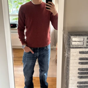 Röd stickad tröja med rund hals - Snygg röd stickad tröja med rund hals och långa ärmar. Perfekt för dig som gillar enkel och stilren design. Tröjan har en normal passform och är gjord i mjukt material som känns skönt mot huden. Passar till jeans eller chinos för en chill look.
