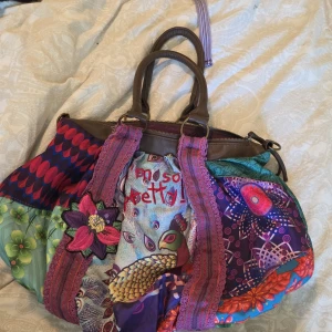 Färgglad handväska från Desigual - Original Desigual-väska i ikonisk patchwork-design med broderad text "Im so pretty!!". Perfekt för dig som gillar att sticka ut med din stil och modellen säljs inte längre i dens webbsida! Ingen retur  🩷     