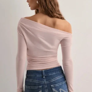 Ljusrosa offshoulder topp från Nelly - Supersnygg ljusrosa offshoulder topp från Nelly i mjuk och stretchig bomullsmix. Modellen är tight och har långa ärmar. Perfekt att styla med jeans eller kjol för en chic look. Tröjan är bara använd kanske två gånger och jag säljer den för att den inte kommit till användning eftersom att den är lite stor på mig! Tröjan har deremot märken på armbågarna inga stora eller så synliga men det där.