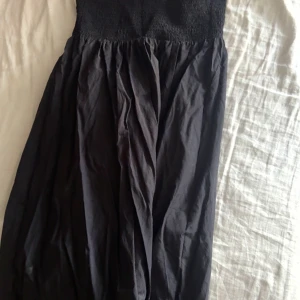 Svart långklänning från Bikbok - Svart långklänning från Bikbok i storlek M. Klänningen har smock upptill som ger en snygg och bekväm passform. Utan axelband 