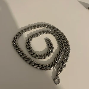 Tjockt silverfärgat kedjehalsband - Säljer ett chunky halsband i silverfärgad metall med breda länkar och karbinlås. Kedjan är ca 2 cm bred och har en clean, stilren look som passar perfekt till streetwear eller för att ge din outfit lite edge.