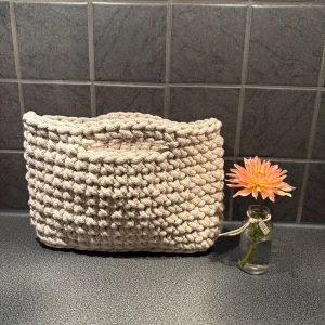 Beige stickad handväska - Säljer en chunky beige handväska med grovt stickat mönster. Perfekt för dig som gillar unika accessoarer och vill ha en väska som sticker ut. Den är mjuk och rymlig, passar till det mesta och har en riktigt mysig vibe.