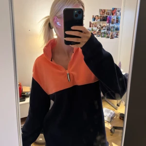 Svart och orange fleece half zip - Oversized fleece-tröja med hög krage och half zip-dragkedja. Sparsamt använt. Säljer för 150kr. Hör av dig vid intresse💕