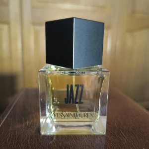 Yves Saint Laurent Jazz Eau de Toilette - Jazz från Yves Saint Laurent är en Eau de Toilette med kryddiga och gröna noter som koriander, geranium, artemisia, cypress och patchouli. Flaskan är stilren och transparent med svart fyrkantigt lock, rymmer 80 ml och har en modern, klassisk vibe. Sprayad en gång.