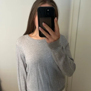Ljusgrå stickad tröja med rund hals - Mysig ljusgrå stickad tröja med rund halsringning och ribbade muddar vid ärmslut och nederkant. Använd sparsamt💞