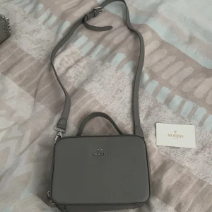 Grå axelväska från Morris Lady - Snygg grå axelväska från Morris Lady i stilren boxig modell. Väskan har justerbar axelrem, topphandtag och silverfärgade detaljer. Väskan är i jätte bra skick använd ett par gånger!:)