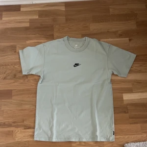 Ljusgrön Nike t-shirt med logga - Nike t-shirt i ljusgrön färg med klassisk svart broderad logga på bröstet. Modellen är rak och har korta ärmar samt rund halsringning. Materialet är mjuk bomull som känns skönt mot huden. Perfekt för dig som gillar enkel och clean streetstil.