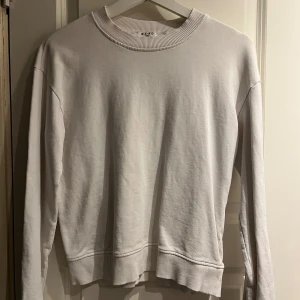 Vit tröja från NA-KD - Säljer en stilren vit tröja från NA-KD i storlek XS. Tröjan har långa ärmar och en rund halsringning med ribbade detaljer vid krage, ärmslut och nederkant. Perfekt för en minimalistisk look.