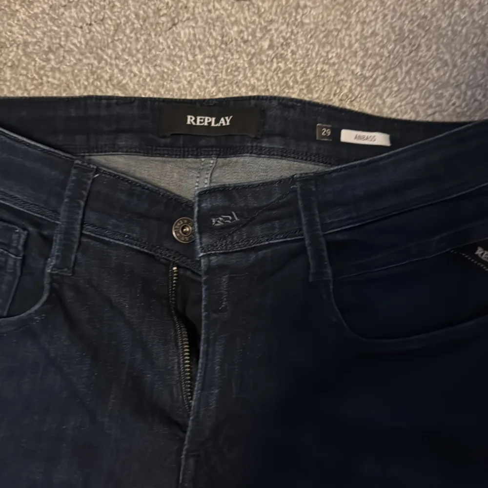 Snygga mörkblå jeans från Replay i modellen Anbass. De har en klassisk femficksdesign och dragkedja. Perfekta för en stilren look.. Farkut & Housut.
