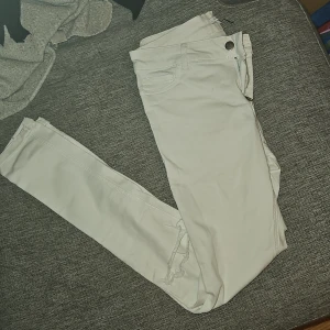 Vita jeans med slitna knän. - Snygga vita jeans med en klassisk design. De har en knapp och dragkedja framtill och är perfekta för en stilren look. Passar bra till både vardag och mer uppklädda tillfällen.