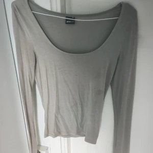 Beige långärmad topp från Gina Tricot - Säljer en stilren grå långärmad topp från Gina Tricot. Toppen har en djup rund halsringning. 💕