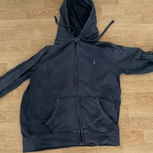 Mörkblå zip hoodie från Polo Ralph Lauren - Säljer en snygg mörkblå zip hoodie från Polo Ralph Lauren. Den har dragkedja framtill och en klassisk broderad logga på bröstet. Tillverkad i 100% bomull för en bekväm känsla. Perfekt för en avslappnad stil. Priset är inte hugget i sten!