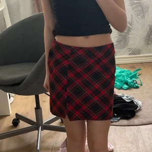 Rutig kjol från H&M - Snygg rutig kjol från H&M i rött och svart. Kjolen har en dragkedja och en knapp på sidan för att enkelt stänga den. Perfekt för en trendig look! Den kostade 300 kr när jag köpte den. Den är använd en gång så den är som ny skick. Den är super söt och jätte skön! 😍