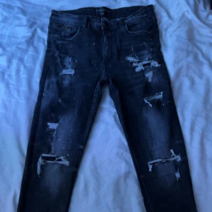Supply & Demand jeans - Snygga svarta Supply & Demand jeans från jd sport med slitna detaljer och dragkedja vid fickan. Perfekta för en cool och avslappnad stil. Midjemått 32W.