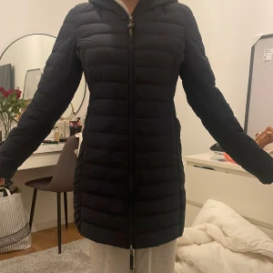 Svart dunjacka med Luva från Parajumpers - Snygg svart dunjacka från Parajumpers med Luva och dragkedja framtill. Jackan har en figur passform och är perfekt för kyligare dagar. Den är långärmad och quiltad för extra värme. En stilren och praktisk jacka för vintern. Den har inga hål eller trasig och har använd den några gånger men ser som ny ut! den är ny tvättad och har inga skador. Jag tar emot swisha eller kontant och möts upp (möts upp i stockholm)