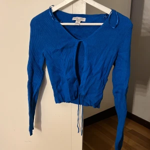 Blå ribbad kofta!  - Säljer en snygg blå ribbad topp från Amisu. Toppen har långa ärmar och en v-ringad design med knytning framtill. Perfekt för en stilren look.