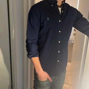 Ralph Lauren Skjorta - Tja säljer en Ralph lauren skjorta i färgen marinblå och i storlek S passar 170-180 cm ungefär. Nypris 1595 KR mitt pris 299 KR. Inga defekter som hål eller fläckar. Skriv vid frågor eller funderingar.