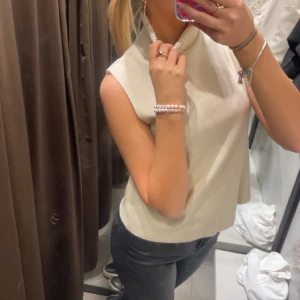 Beige ärmlös polotopp - Snygg beige ärmlös polotopp i ett mjukt material. Perfekt för lager-på-lager eller att bära som den är. Enkel och stilren design som passar till många olika outfits. Säljer då den inte kommer till användning. Den är använd en gång. 