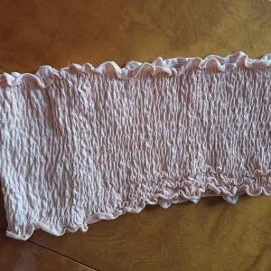 Ljusrosa smockad tubtopp - Säljer en söt ljusrosa tubtopp från Soc Toppen är smockad med volangdetaljer längs kanterna. Perfekt för varma dagar och kan enkelt matchas med olika outfits.