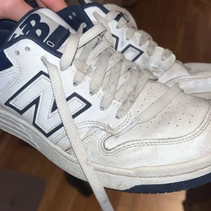 Vita och blå sneakers från New Balance - Snygga vita sneakers från New Balance med blå detaljer och klassisk snörning. Perfekta för en avslappnad stil. Gummisula med bra grepp och stor 'N'-logga på sidan. Pris kan diskuteras