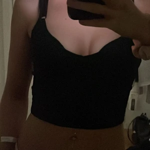 Svart ribbad linnetopp - Snygg svart ribbad linnetopp med smala axelband och en v-ringad design. Perfekt för en stilren look.