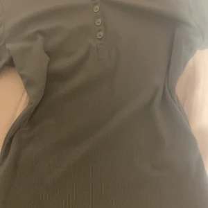 Grön ribbad långärmad topp - Säljer en stilren grön ribbad topp med långa ärmar och knappar framtill. Perfekt för en avslappnad look. Står ingen storlek på den men den passar xs-s. Testad bara. 