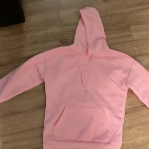 Rosa hoodie - Säljer en mysig rosa hoodie med känguruficka och justerbar huva. Perfekt för en avslappnad stil och bekväma dagar.