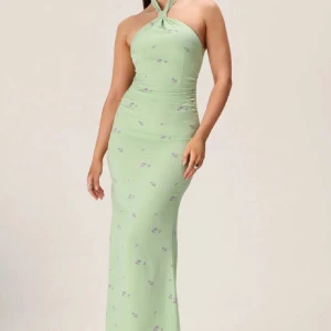 Grön långklänning med blommönster - Elegant grön långklänning med ett blommönster. Klänningen har en halterneck-design och en tight passform som framhäver figuren. Perfekt för sommarens festligheter. Säljer då den inte kommit till så mycket användning 