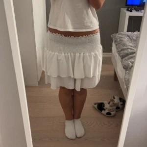 Två volangkjolar i vitt och svart - Säljer två söta volangkjolar, en i vitt och en i svart. Båda har en elastisk midja och flera lager volanger som ger en lekfull look. Perfekta för sommarens alla tillfällen! 🖤🤍40kr för båda 🥰