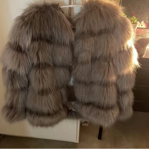 Grå pälsjacka - Säljer en lyxig och fluffig grå pälsjacka som är perfekt för kyliga dagar. Jackan har en elegant design med långa ärmar och en mjuk, voluminös look. Den är idealisk för att hålla dig varm och stilfull under vintern.
