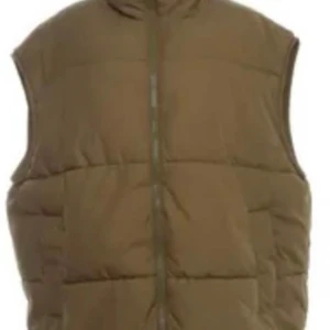Olivfärgad dunväst - Säljer en olivfärgad dunväst med dragkedja. Perfekt för kyligare dagar och ger en stilren look. Västen är ärmlös och har en hög krage för extra värme.