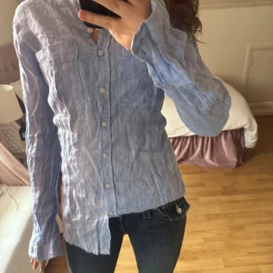 Blå skjorta från Gina Tricot - Snygg blå skjorta från Gina Tricot i storlek 34. Skjortan har långa ärmar och knappar framtill. Perfekt för en stilren look.