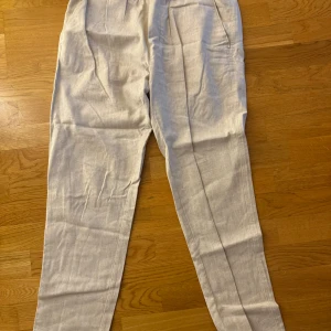 Beige  linnebyxor - Snygga beige linnebyxor med elastisk midja och avslappnad passform. Perfekta för en bekväm och stilren look. Byxorna har en rak design och är tillverkade i ett lätt och luftigt material.