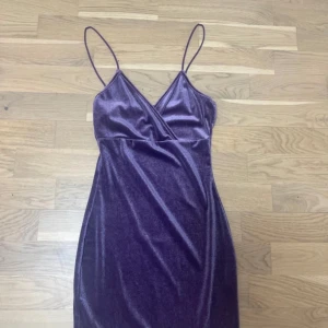 Lila klänning/fioletowa sukienka  - Snygg lila klänning i sammet med smala axelband och omlott-design. Perfekt för en kväll ute eller en speciell tillställning. Den har en elegant och figurnära passform som framhäver silhuetten. Materialen är stretchiga så den skulle passa någon som är en storlek större.