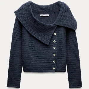 Mörkblå stickad topp från Zara - Snygg mörkblå stickad topp från Zara med en unik offshoulder-design och knappar framtill. Perfekt för att ge en stilren touch till din outfit. Toppen har används ett fåtal gånger men skicket är som nytt! 