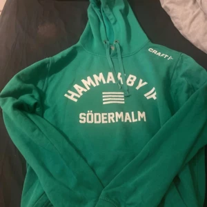 Hammarby if hoodie från Craft - Säljer en grön hoodie från Craft med texten 'Hammarby IF Södermalm' tryckt i vitt på framsidan. Hoodien har en klassisk design med dragsko i huvan och långa ärmar. Perfekt för att visa ditt stöd för laget!