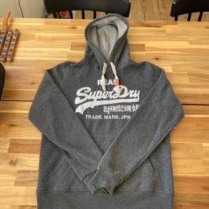 Grå hoodie från Superdry - Säljer en snygg och skön grå hoodie från Superdry i 100% bomull. S i storlek och är i toppen skick, utan defekter! Skriv vid minsta lila fundering😁! Vid snabb affär så är priset diskuterbart