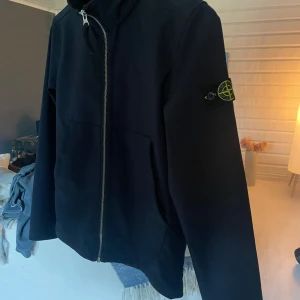 Svart jacka från Stone Island - Snygg svart jacka från Stone Island. Riktigt fint skick och använd väldigt sparsamt. Säljer den då den inte passar mig längre, den är i junior storlek och passar den som är upp till 174-175