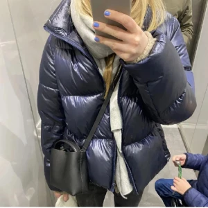 Mörkblå pufferjacka - Snygg och varm mörkblå pufferjacka med dragkedja. Perfekt för kyliga dagar med sin quiltade design och höga krage. Jackan har en glansig finish som ger en modern look. Skriv för bild på defekt!litet hål💕
