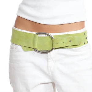 Limegrönt mockabälte med nitar - Snyggt limegrönt bälte i mocka med stora silverfärgade nitar och en rund spänne. Perfekt för att ge din outfit en cool touch. Passar bra till både jeans och klänning.