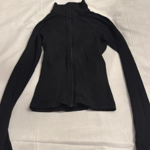 Svart långärmad träningskofta  - Koftan sitter tajt och fint från GinaTricot. 