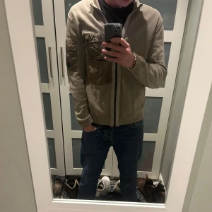 Beige stickad tröja från C.P. Company - Säljer en beige stickad tröja från C.P. Company med dragkedja och hög krage. Tröjan har en unik ficka med knappdetalj på ärmen och en dragkedjeficka på bröstet. Perfekt för höst och vinter. Nypris ligger runt 4000kr. Kvitto och tags samt extra knappar finns. Hör av dig vid eventuella frågor!