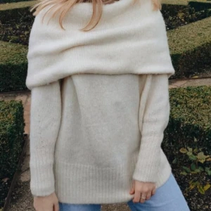 Beige stickad offshoulder tröja - Mysig beige stickad tröja med offshoulder-design. Perfekt för kyliga dagar med sin långa ärmar och mjuka material. En stilren och bekväm tröja som passar till många tillfällen.